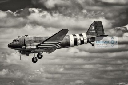 Black and white C47 Dakota wearing D Day invasion stripes. Side view of aeroplane as it lands