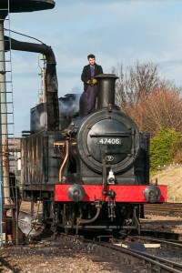 Train driver standing on top of a Class 3F Jinty steam loco as it takes on water at Loughborough on the Great Central Railway