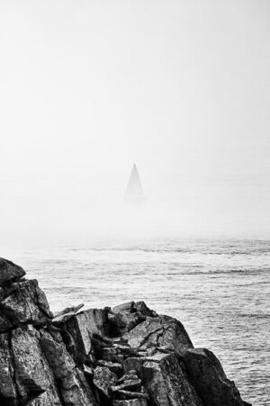 Sailboat disappearing into the sea mist at Pointe du Ra in Brittany