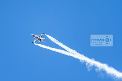 Belgian Air Force F-16 aeroplane trailing white vapour trails during an airshow display