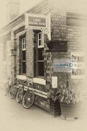 Antique effect photo of a 1960s scene showing 2 bicycles leaning against a station building.