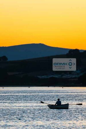 Silhoutte of a man rowing on the River Teign as the sun sets over Dartmoor in the background