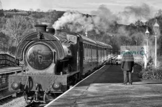 Black and white view of the station master waiting on the platform at Darley Dale railway station as a passenger train arrives