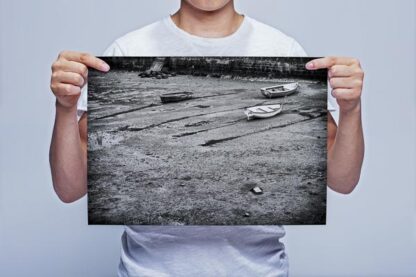 Man Holding Black and White Boats on a Beach Wall Art Prints