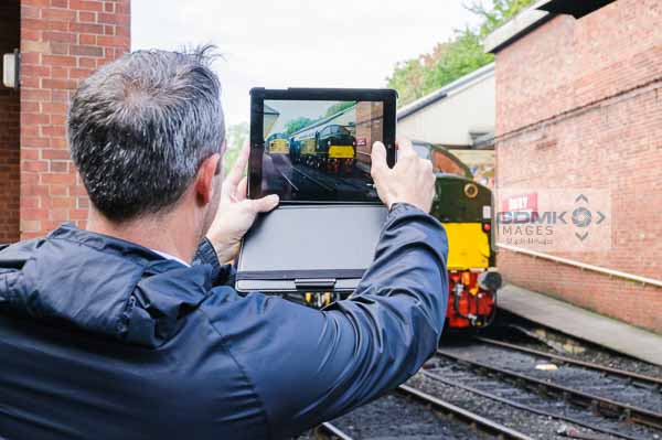 A rail enthusiast taking a picture of class 37 and class 40 locos at Bury on the East Lancs Railway