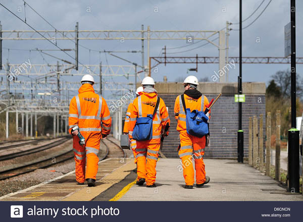 Railway maintenance staff walking along a station platform